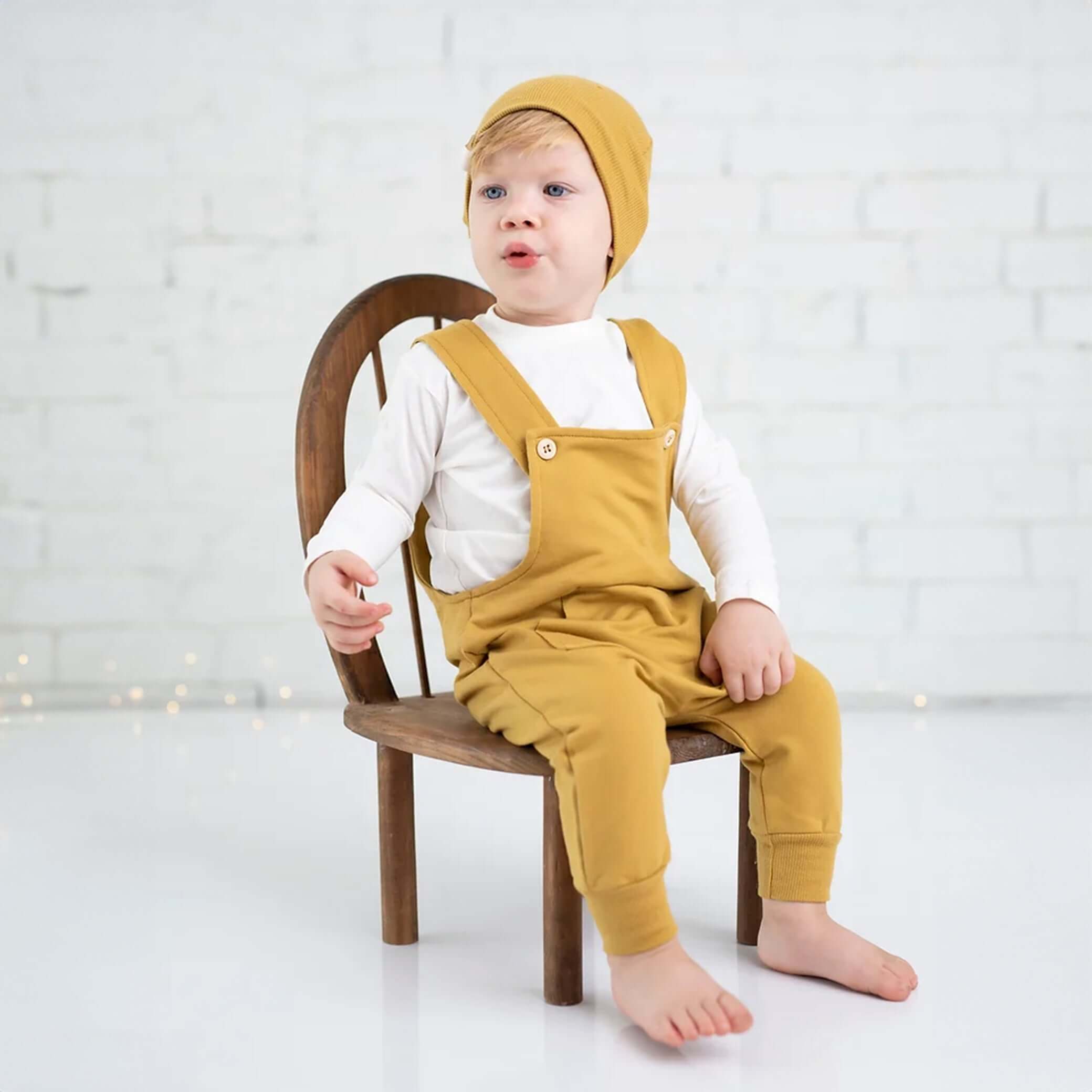 Ein Baby trägt 3-teiliges Set, Overall + Pullover + Mütze