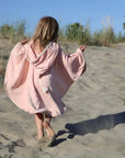 ein Kind im Powder Rabbit Badecape am Strand