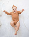 Baby traegt Bio-Klassische-Knotenmuetze in Ingwer