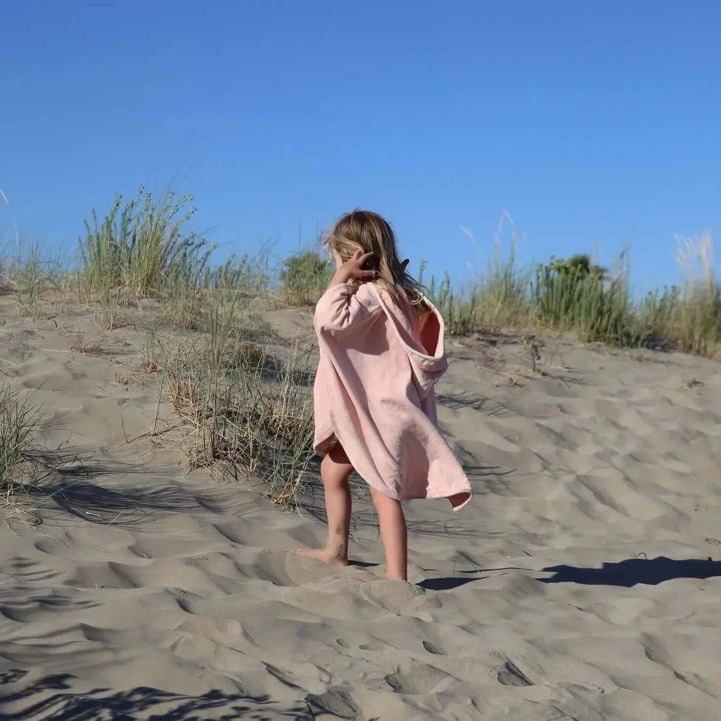 ein Kind am Strand, das den Powder Rabbit Badecape trägt