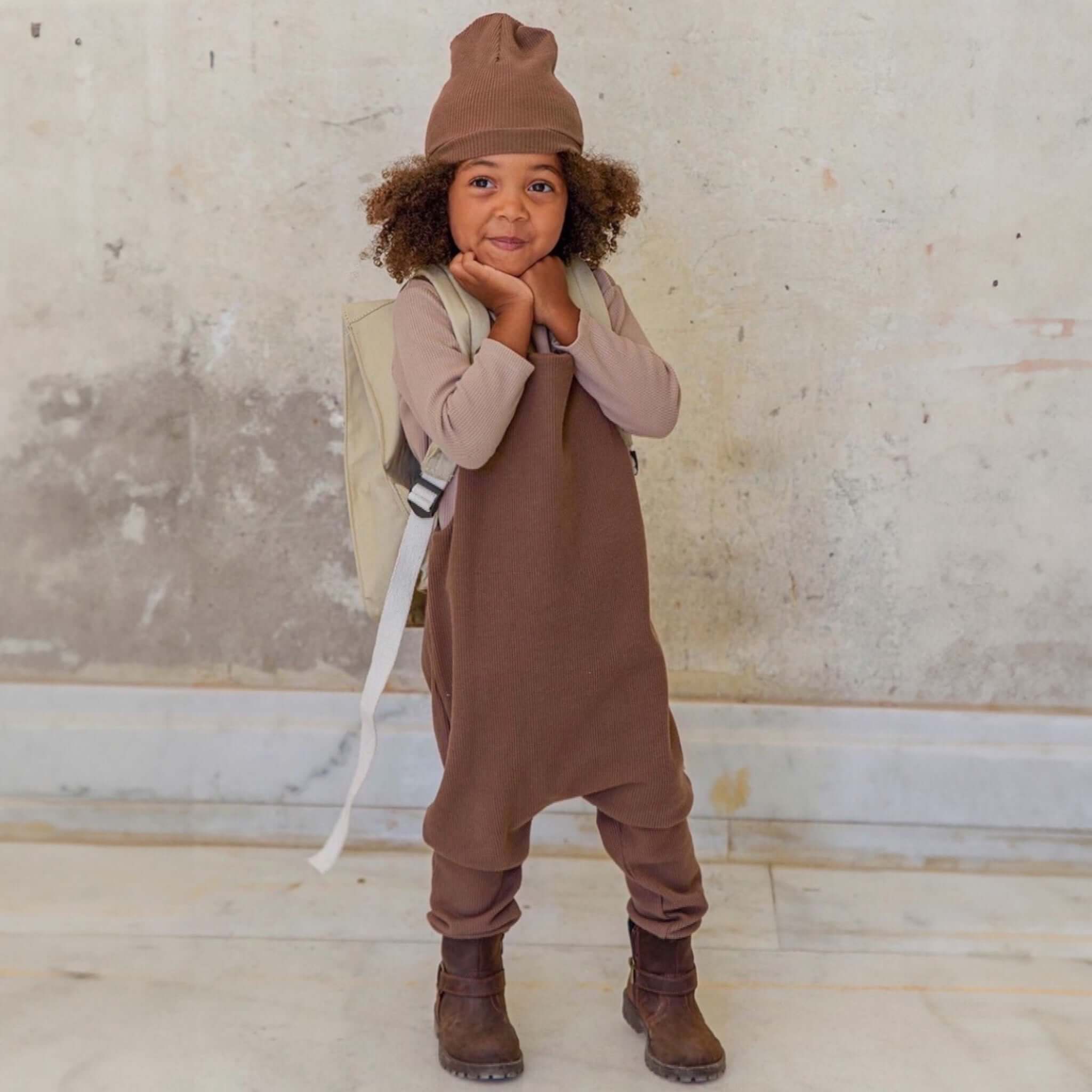 Ein Kind, das ein 3er-Set Natural Waffle Overall + Pullover + Mütze in Braun trägt