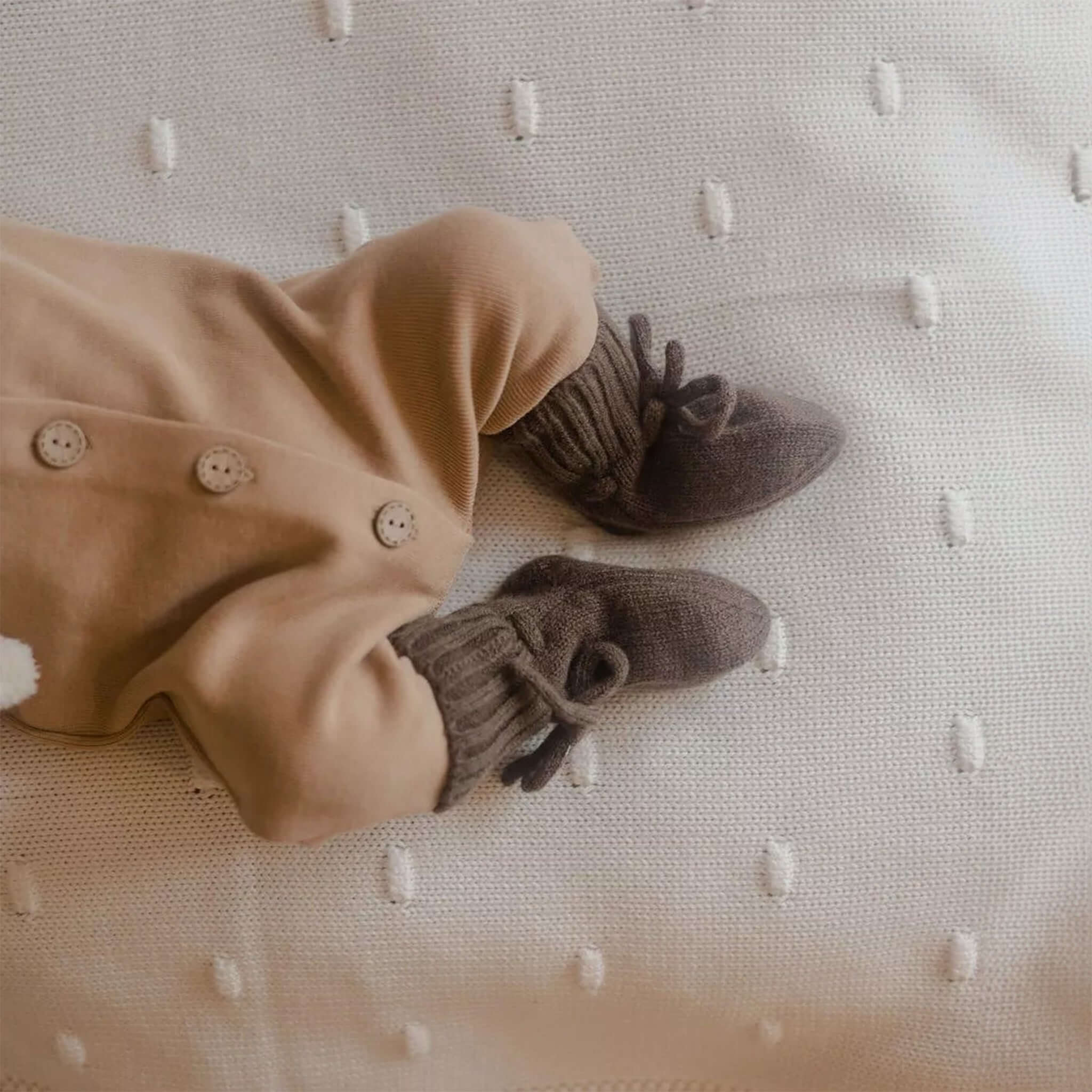 Ein Baby, das Hausschuhe aus Merinowolle in Mokka trägt - Close-up