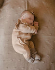 ein Baby trägt Hausschuhe aus Merinowolle in Kamel