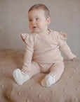 Baby trägt Baby-Hausschuhe aus Merinowolle in Creme