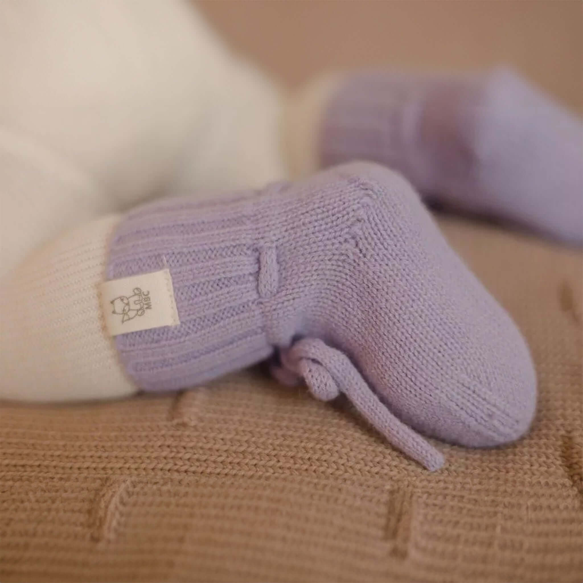 Baby trägt Hausschuhe aus Merinowolle in Lavendel