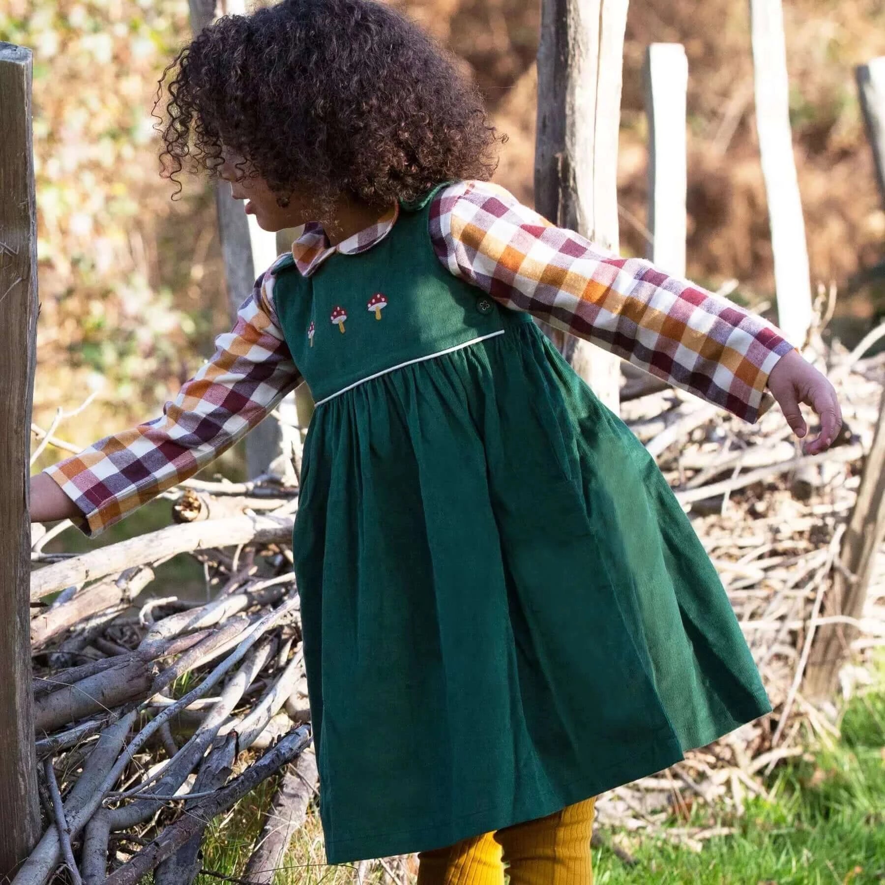 Kind Trägt Besticktes Toadstool Cord Pinny Kleid