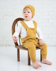 Ein Baby trägt 3-teiliges Set, Overall + Pullover + Mütze