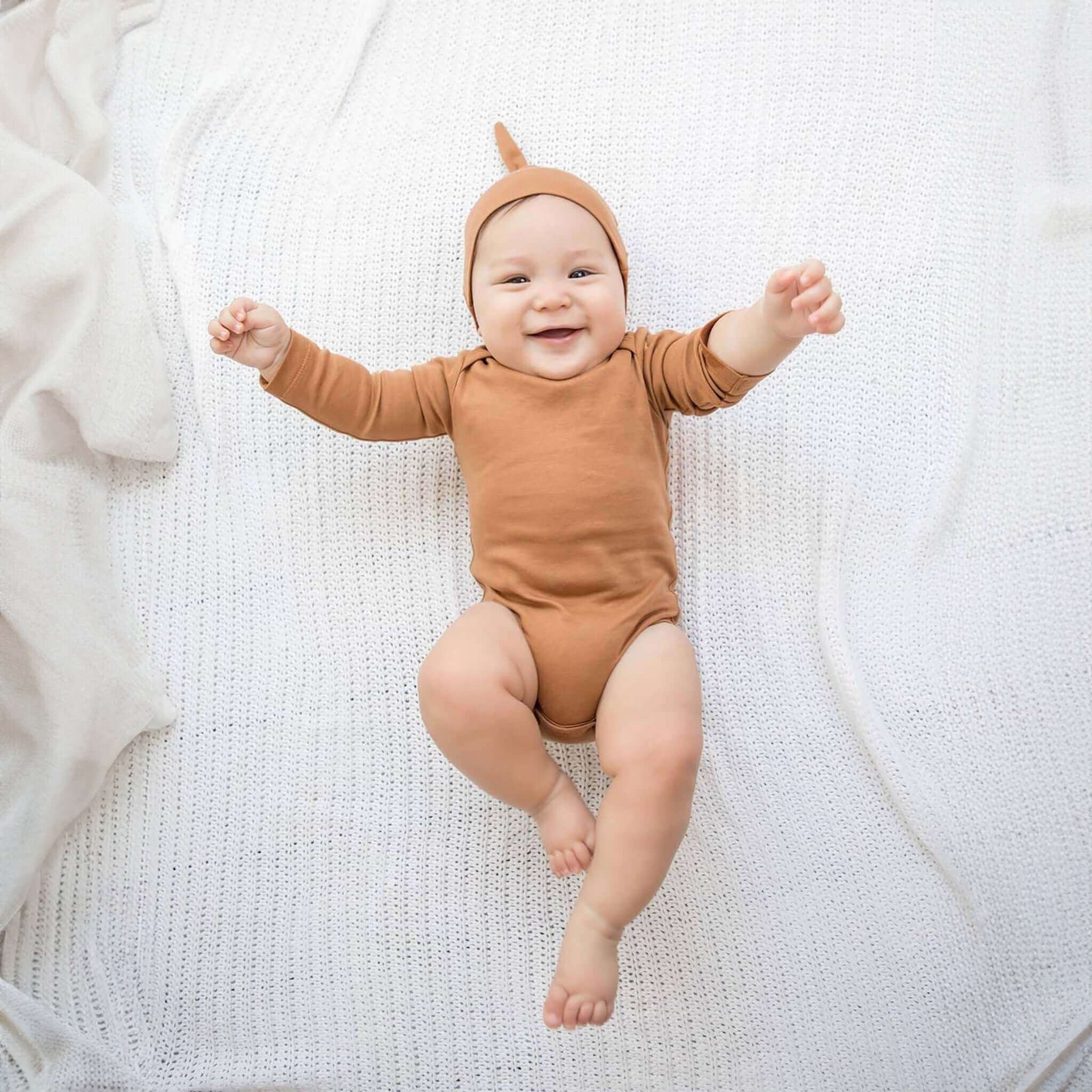 Baby traegt Bio-Klassische-Knotenmuetze in Ingwer