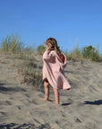ein Kind am Strand, das den Powder Rabbit Badecape trägt