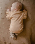 Ein schlafendes Baby, das Hausschuhe aus Merinowolle in Creme trägt