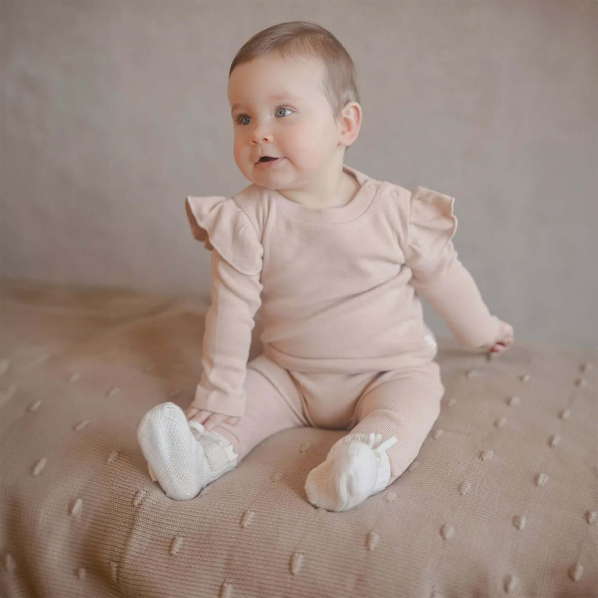 Baby trägt Baby-Hausschuhe aus Merinowolle in Creme