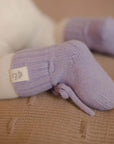 Baby trägt Hausschuhe aus Merinowolle in Lavendel