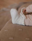 ein Baby trägt Baby-Hausschuhe aus Merinowolle in Creme- Close-up
