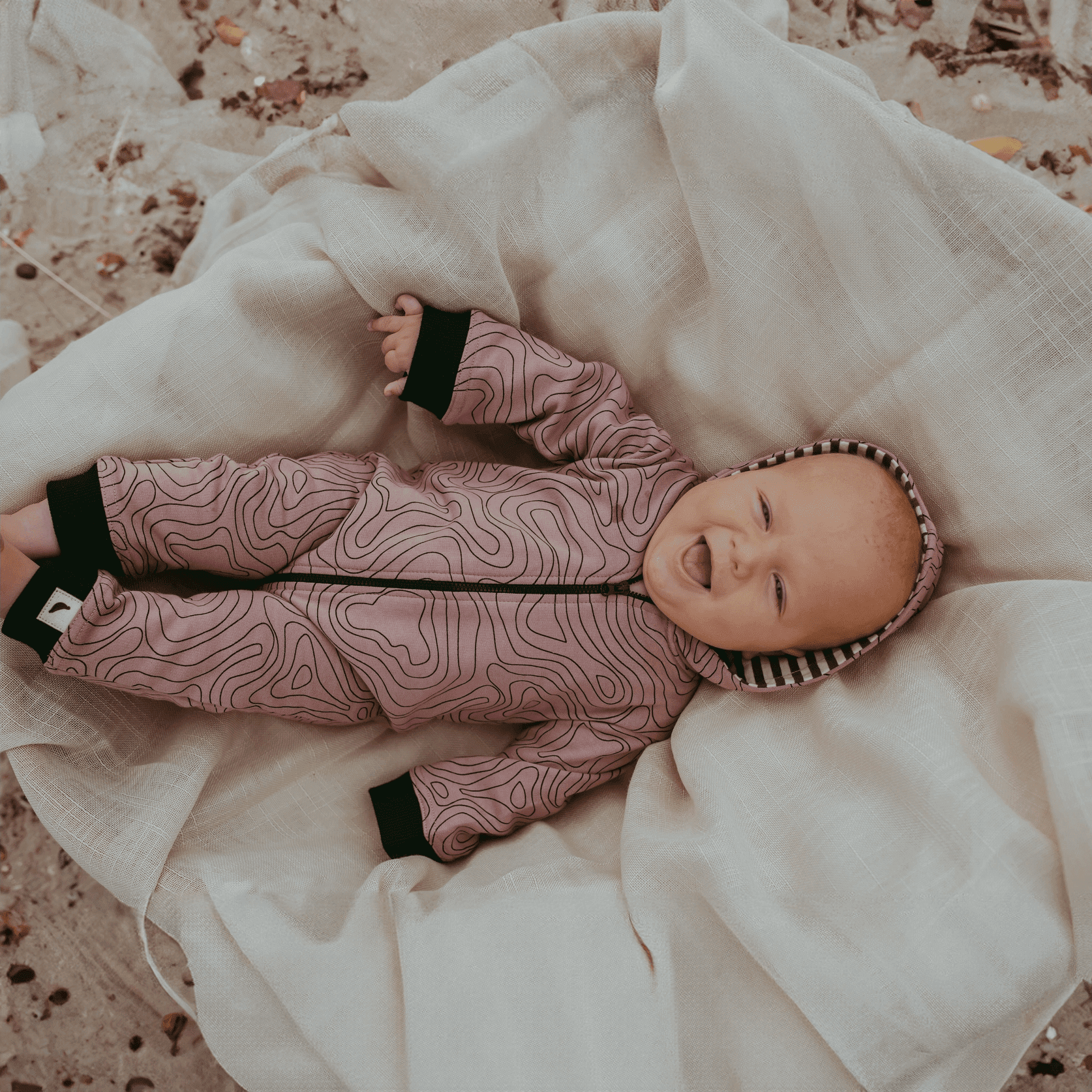 Ein glückliches Baby, das einen Strampler mit Kontur-Print trägt
